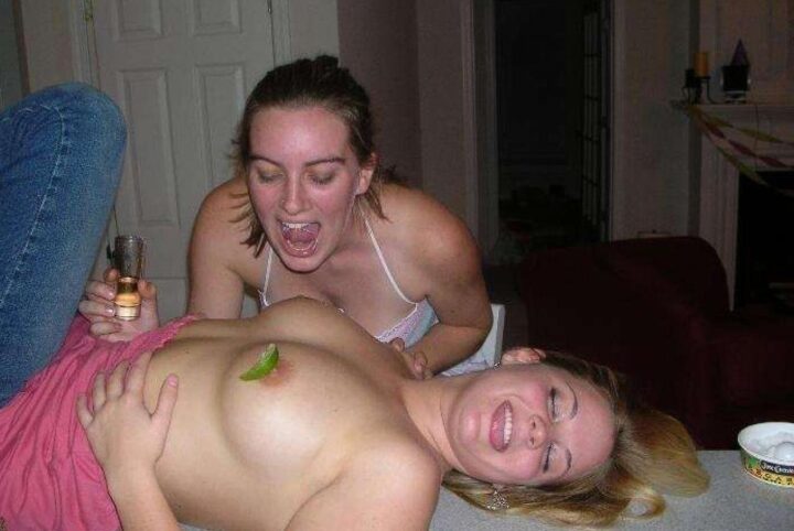 Одна пьяная девушка лежит с голыми сиськами, а другая слизывает с нее