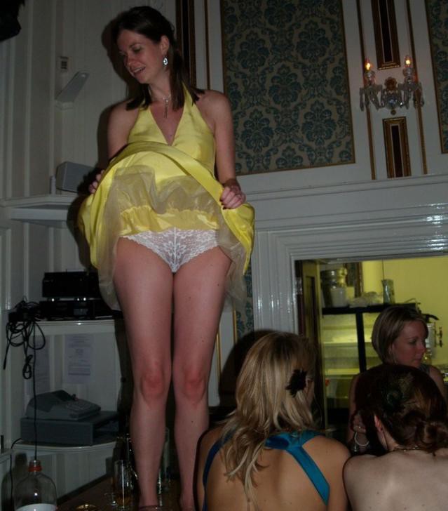 Веселая и интересная девушка в желтом платье танцует на столе с поднятым платьем